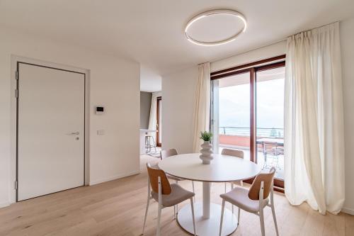 a white dining room with a white table and chairs at Bella Lì - by MyHomeInComo in Menaggio