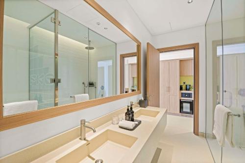 a bathroom with a sink and a large mirror at Fuwairit Kite Beach, Tapestry Collection By Hilton in Fuwayriţ