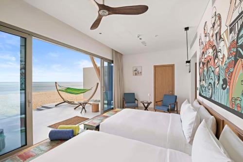 a bedroom with a bed and a view of the beach at Fuwairit Kite Beach, Tapestry Collection By Hilton in Fuwayriţ