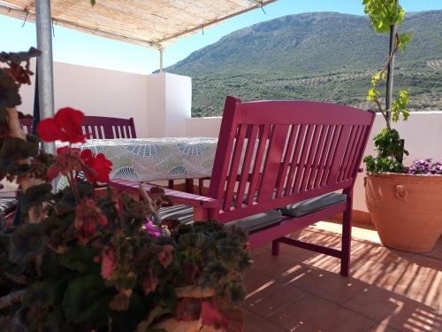 a red bench on a patio with a table and flowers at Casa Holmes in Las Casillas