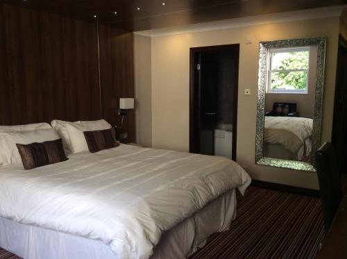 een slaapkamer met een groot wit bed en een spiegel bij Briars Hall Hotel in Burscough