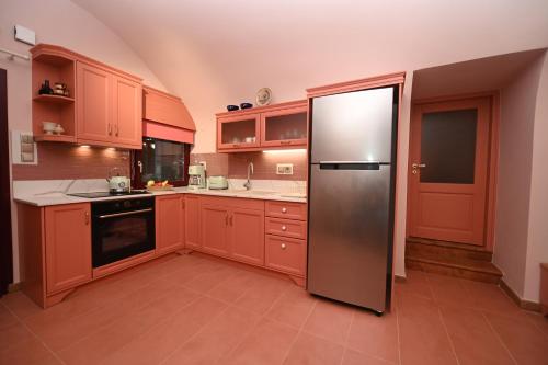 a kitchen with red cabinets and a stainless steel refrigerator at PhiloXenia Traditional Apartments in Chios