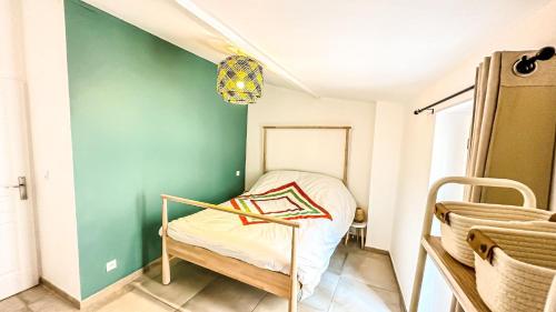 Cette petite chambre comprend un lit et un mur vert. dans l'établissement Les Iris, à Céreste