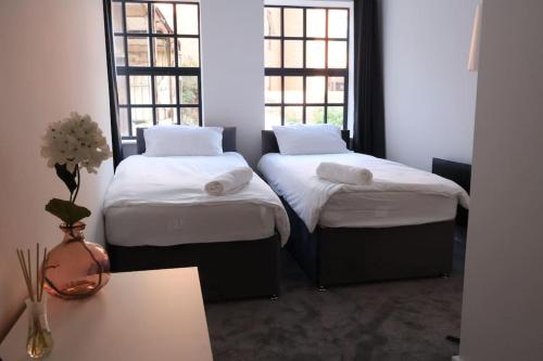 two beds in a room with two windows at Modern house in Birmingham in Birmingham