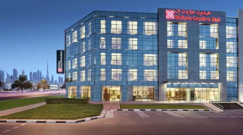 ein hohes Glasgebäude mit einem Schild darauf in der Unterkunft Hilton Garden Inn Dubai Al Mina - Jumeirah in Dubai