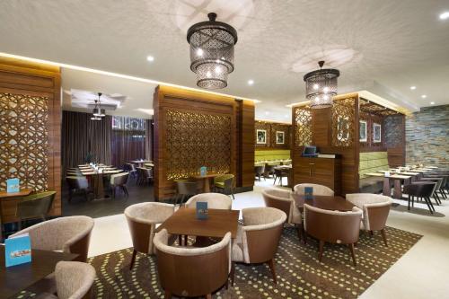 ドバイにあるHilton Garden Inn Dubai Al Muraqabat - Deiraのテーブル、椅子、テーブル、テーブルトップが備わるレストラン