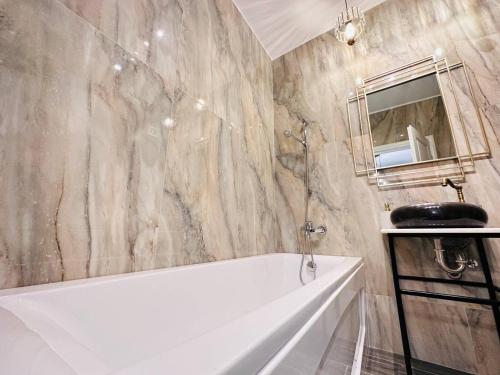a bathroom with a white tub and a marble wall at RHUM B02 - Liberty in Bucharest