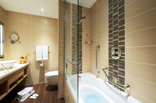 a bathroom with a tub and a toilet and a sink at Hilton Garden Inn Dubai, Mall Avenue in Dubai