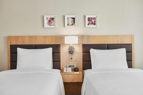 two beds in a hotel room with white sheets at Hilton Garden Inn Dubai, Mall Avenue in Dubai