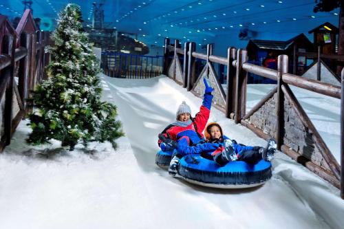 two people riding on a snowledge down a slide at Hilton Garden Inn Dubai, Mall Avenue in Dubai