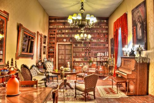 Hacienda El Carmen Hotel & Spa في Portes Gil: غرفة مع مكتبة فيها بيانو وكراسي