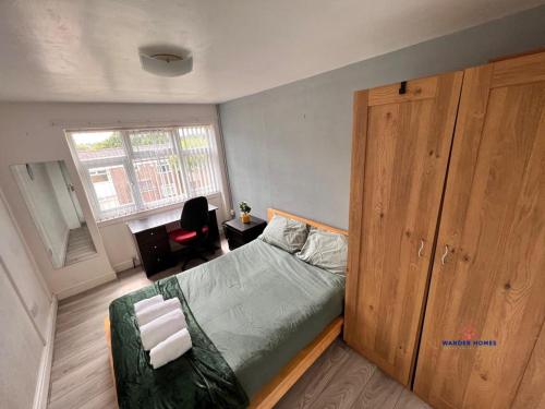 - une chambre avec un lit et une armoire en bois dans l'établissement Ensuite Rooms Birmingham Underwood Close, à Birmingham