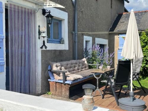 a couch on a patio with a table and an umbrella at Maison Lavande in Blismes
