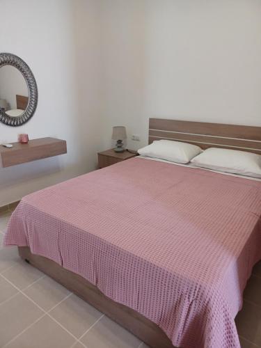 a bedroom with a bed with a pink blanket at Pension Annoula in Archangelos