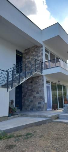 a white house with a balcony and a staircase at Villa Twins Dojran in Nov Dojran