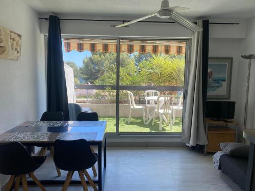 d'un salon avec une table, des chaises et une porte coulissante en verre. dans l'établissement BALI Studio Climatisé, à La Ciotat