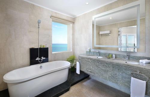 een badkamer met een groot bad en een grote spiegel bij Hilton Hurghada Plaza Hotel in Hurghada