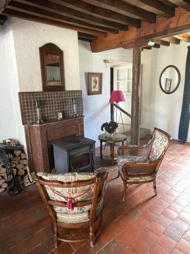a living room with a wood stove and chairs at Maison Lavande in Blismes