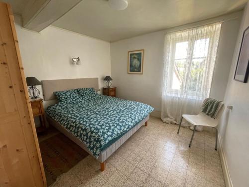 1 dormitorio con cama, ventana y silla en Maison Lavande en Blismes