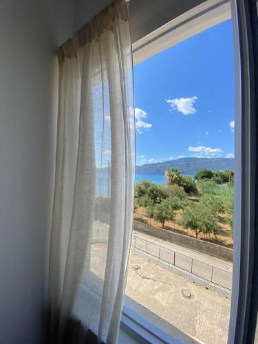 a window with a view of the ocean at Thassa Beach Apartment No1 (with mountain view) in Leonidion