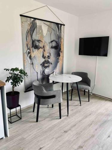 una mesa y sillas en una habitación con una pintura en Flat - WiFi + SmartTV + Balcony en Sankt Augustin