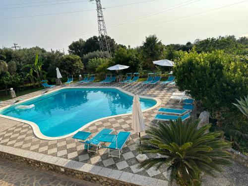 uma piscina com cadeiras azuis e guarda-sóis em Hotel Royal em Coccorino