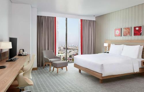 a hotel room with a bed and a desk with a computer at Hilton Garden Inn Muscat Al Khuwair in Muscat