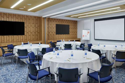 a conference room with tables and chairs and a screen at Hilton Garden Inn Muscat Al Khuwair in Muscat