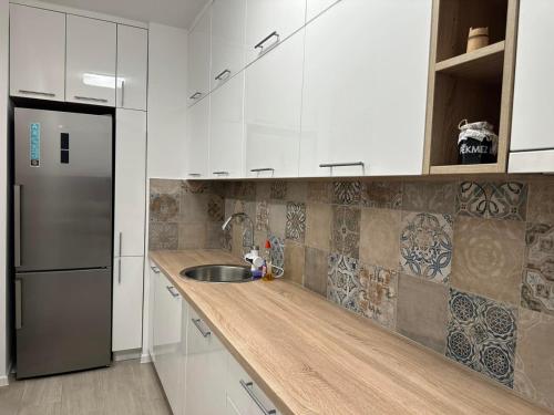 una cucina con armadi bianchi e frigorifero in acciaio inossidabile di Novouređen stan u Vitezu a Vitez