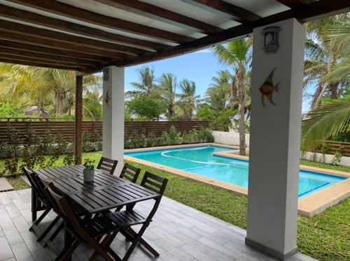 un patio con mesa y sillas junto a una piscina en CASA MOZITA en Vilanculos
