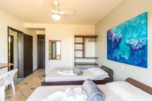 a room with two beds and a painting on the wall at Pousada Caminho do Mar in Bombinhas