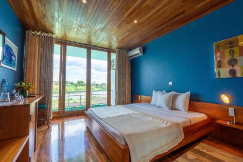 a bedroom with a large bed with a blue wall at Hostellerie de la Sanaga in Edéa