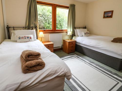a bedroom with two beds and a window at 1 Sandholm in Mallaig