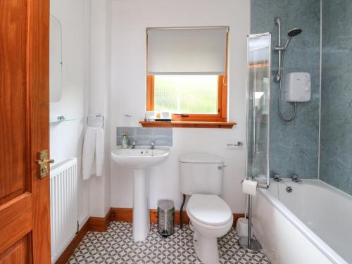 a bathroom with a toilet and a sink and a tub at 1 Sandholm in Mallaig