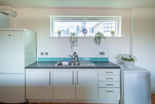 a white kitchen with a sink and a window at Stunning 2Bed BRICK LANE Apartment in London