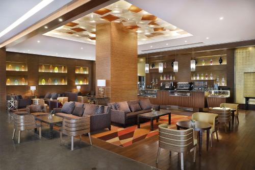 eine Hotellobby mit Sofas, Tischen und einer Bar in der Unterkunft Hilton Riyadh Hotel & Residences in Riad