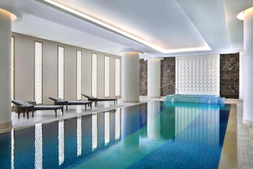 a swimming pool with chairs and tables in a building at Hilton Riyadh Hotel & Residences in Riyadh