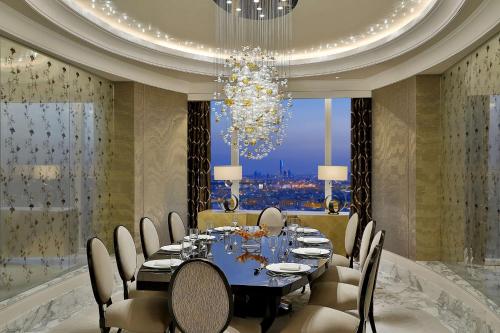 a dining room with a table and chairs and a chandelier at Hilton Riyadh Hotel & Residences in Riyadh