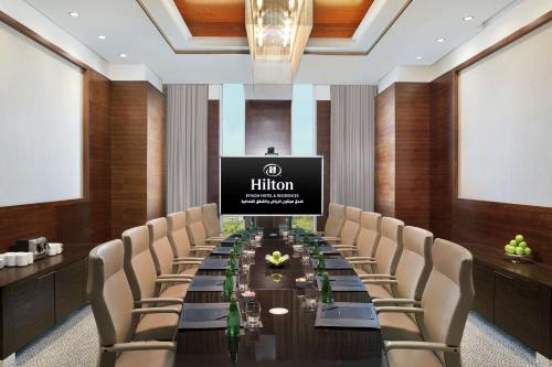 a conference room with a long table with chairs and a screen at Hilton Riyadh Hotel & Residences in Riyadh