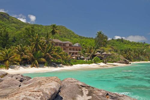 um resort numa praia com palmeiras e o oceano em DoubleTree by Hilton Seychelles Allamanda Resort & Spa em Takamaka
