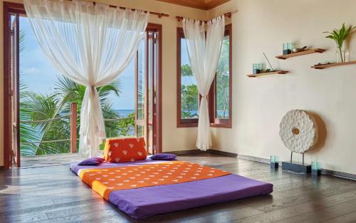 a bedroom with a large bed in a room with windows at DoubleTree by Hilton Seychelles Allamanda Resort & Spa in Takamaka