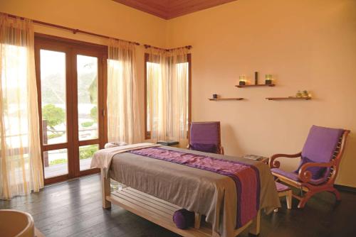 a bedroom with two chairs and a bed and a window at DoubleTree by Hilton Seychelles Allamanda Resort & Spa in Takamaka