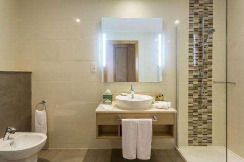 a bathroom with a sink and a toilet and a mirror at Hilton Garden Inn Tanger City Center in Tangier