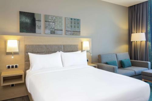 a bedroom with a large white bed and a chair at Hilton Garden Inn Tanger City Center in Tangier