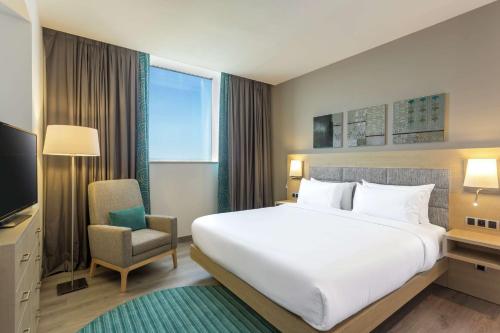 a hotel room with a large bed and a chair at Hilton Garden Inn Tanger City Center in Tangier