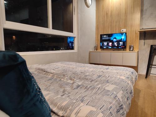 達沃市的住宿－The Zen Suites at Mesatierra Garden Residences，一间卧室配有一张床和一台平面电视
