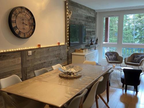 une salle à manger avec une table et une horloge au mur dans l'établissement Appartement rénové 7/8 pers, au calme avec balcon, parking et wifi inclus, au centre de la station - FR-1-346-307, à Arc 1800