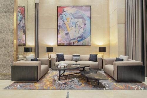 a lobby with couches and a table and a painting at Hilton Doha The Pearl in Doha