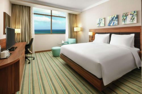 a hotel room with a bed and a desk and a television at Hilton Garden Inn Al Jubail in Al Jubail