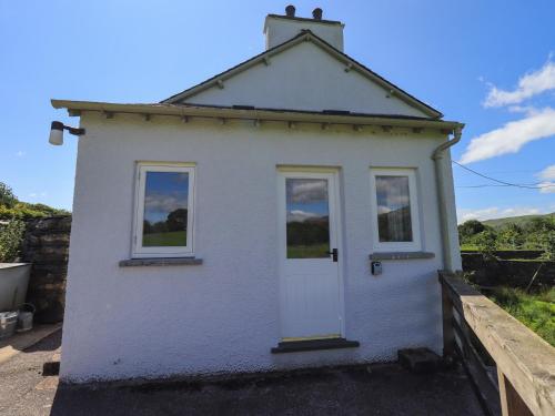 a small white house with a white door and windows at Ellis Howe in Coniston